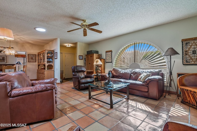 living room featuring tile patterned floors, ceiling fan with notable chandelier, and a textured ceiling