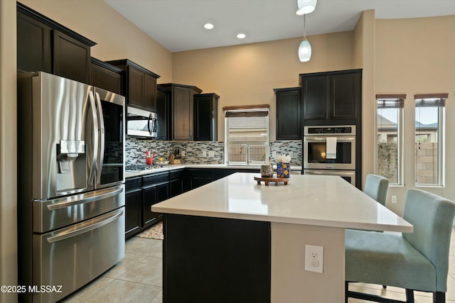 kitchen featuring a kitchen island, appliances with stainless steel finishes, backsplash, a kitchen breakfast bar, and hanging light fixtures