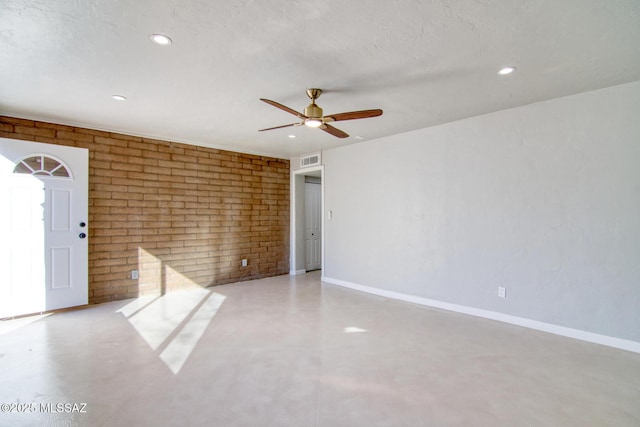 spare room featuring ceiling fan, brick wall, and a textured ceiling