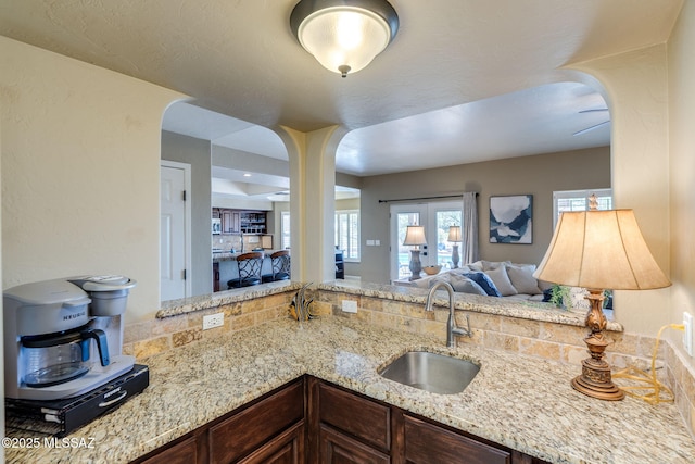1943 W Desert Highlands Dr, Oro Valley, AZ 85737 - kitchen with a sink, arched walkways, open floor plan, light stone counters, and dark brown cabinets