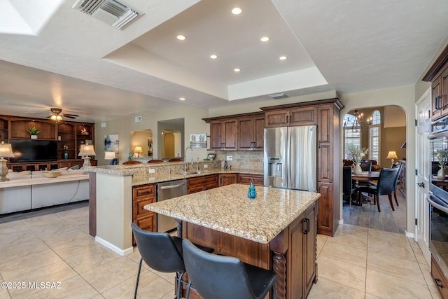 1943 W Desert Highlands Dr, Oro Valley, AZ 85737 - kitchen featuring stainless steel appliances, arched walkways, a sink, a peninsula, and light stone counters