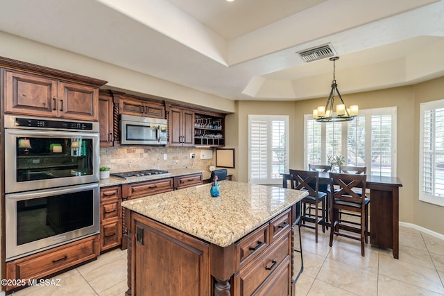 1943 W Desert Highlands Dr, Oro Valley, AZ 85737 - kitchen featuring appliances with stainless steel finishes, a chandelier, decorative backsplash, light stone counters, and light tile patterned floors