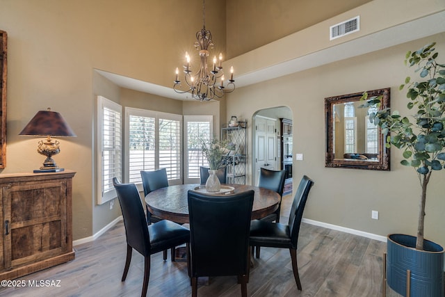 1943 W Desert Highlands Dr, Oro Valley, AZ 85737 - dining space featuring arched walkways, a chandelier, baseboards, wood finished floors, and a high ceiling