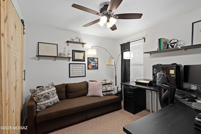 carpeted office space featuring a barn door and ceiling fan