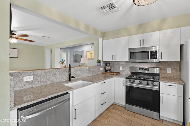 kitchen featuring white cabinetry, tasteful backsplash, appliances with stainless steel finishes, and light stone counters