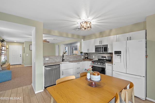 kitchen with tasteful backsplash, stainless steel appliances, sink, and white cabinets