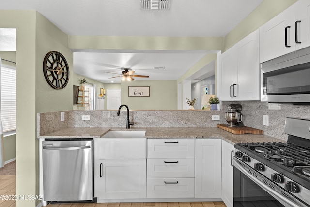 kitchen with stainless steel appliances, light stone countertops, sink, and white cabinets