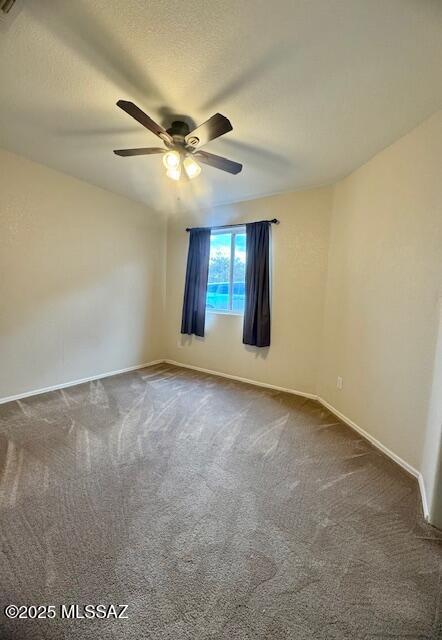 carpeted empty room featuring ceiling fan and a textured ceiling