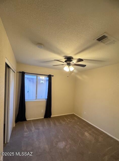 unfurnished room with ceiling fan, a textured ceiling, and dark carpet