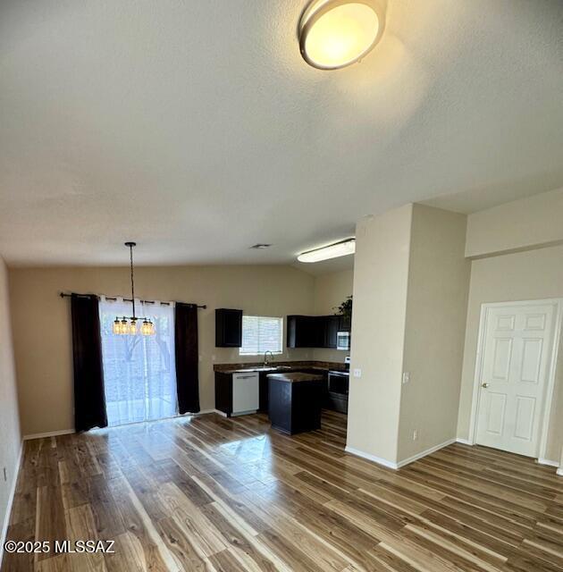 kitchen featuring lofted ceiling, a textured ceiling, dark hardwood / wood-style floors, a notable chandelier, and stove