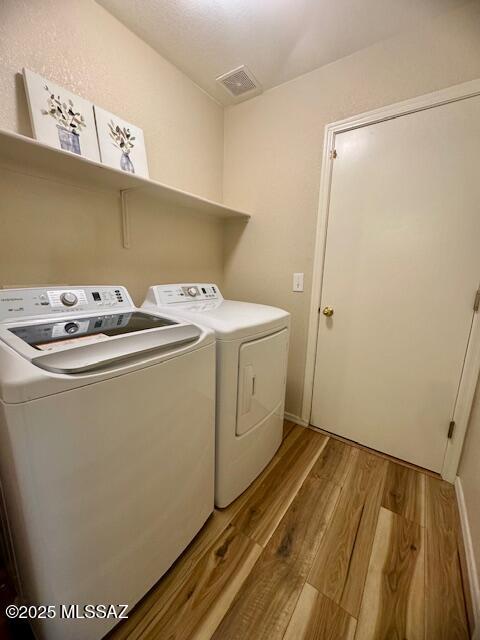 laundry room with washing machine and dryer and light hardwood / wood-style flooring