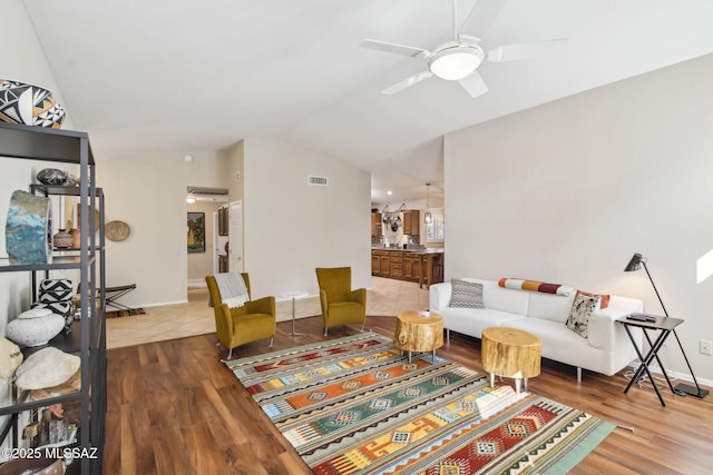 living room with hardwood / wood-style flooring, ceiling fan, and lofted ceiling