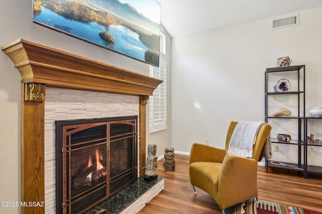 living area featuring hardwood / wood-style floors and a stone fireplace