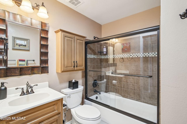 full bathroom with toilet, vanity, and bath / shower combo with glass door