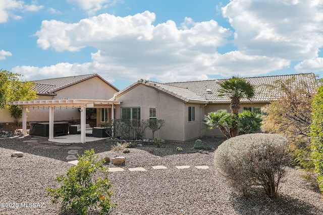 back of house with a hot tub, a pergola, and a patio