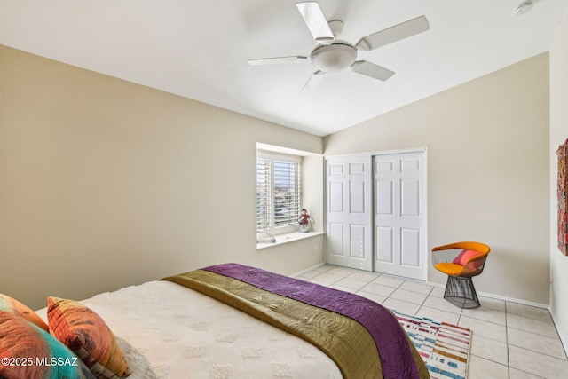 tiled bedroom with vaulted ceiling, ceiling fan, and a closet