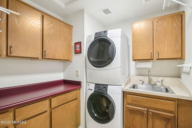 washroom featuring sink, cabinets, and stacked washer and clothes dryer