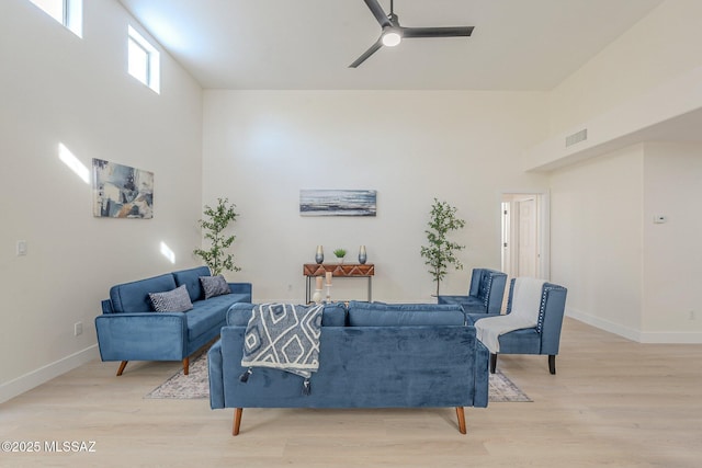 living room with ceiling fan, light hardwood / wood-style flooring, and a high ceiling