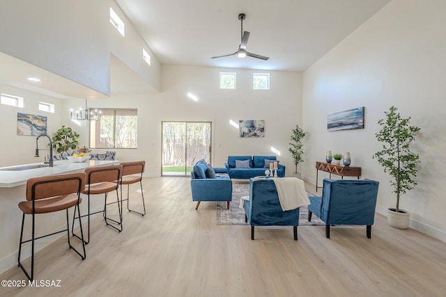 living room featuring a towering ceiling, plenty of natural light, sink, and light wood-type flooring