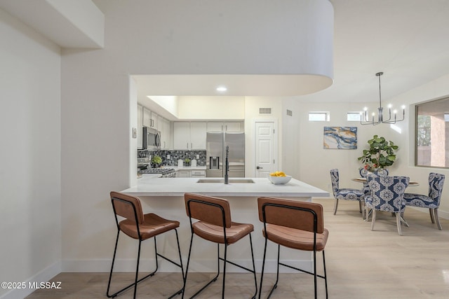 kitchen featuring white cabinetry, sink, backsplash, kitchen peninsula, and stainless steel appliances