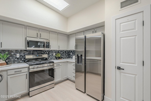 kitchen featuring gray cabinets, tasteful backsplash, and appliances with stainless steel finishes