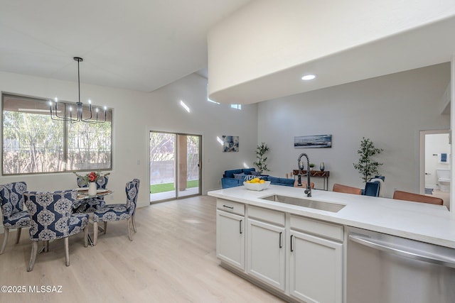 kitchen with sink, white cabinetry, light wood-type flooring, dishwasher, and pendant lighting