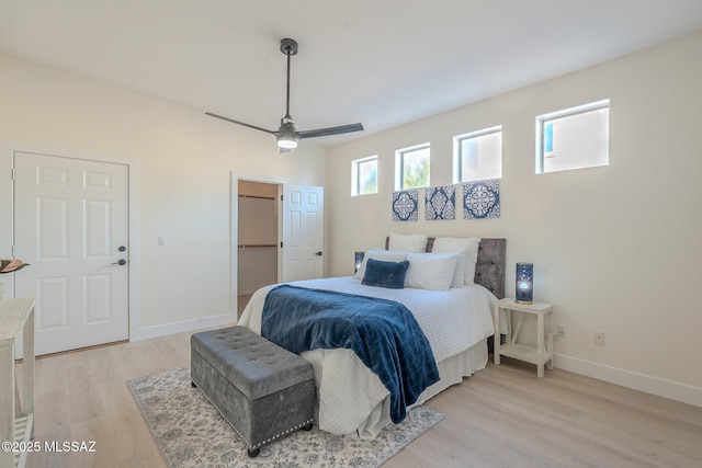 bedroom with ceiling fan, light hardwood / wood-style flooring, and a walk in closet