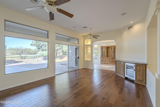 unfurnished living room featuring ceiling fan, wine cooler, and dark hardwood / wood-style flooring