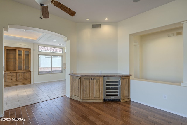 bar with ceiling fan, beverage cooler, and dark hardwood / wood-style flooring