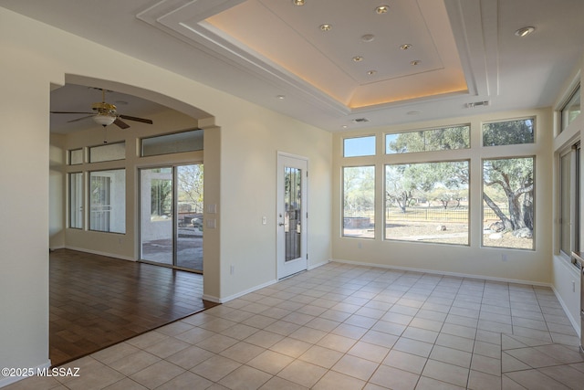 unfurnished sunroom with a raised ceiling and ceiling fan