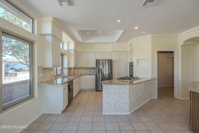 kitchen featuring tasteful backsplash, white cabinets, light tile patterned floors, light stone counters, and stainless steel appliances