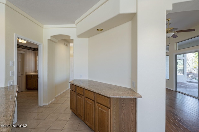 kitchen featuring light stone counters, ceiling fan, and light tile patterned floors