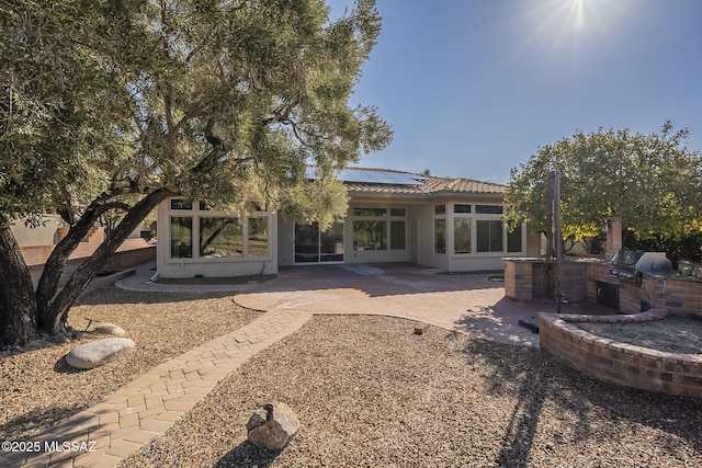 rear view of property with a patio, solar panels, and exterior kitchen