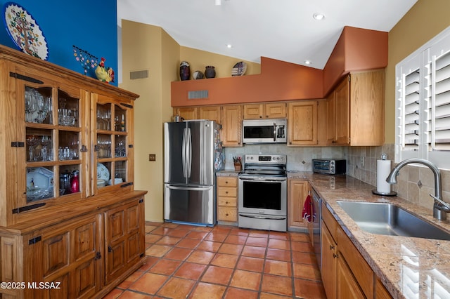 kitchen with sink, appliances with stainless steel finishes, tasteful backsplash, light stone counters, and light tile patterned flooring