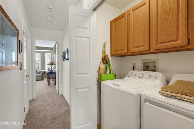 washroom featuring cabinets, washing machine and dryer, and light colored carpet