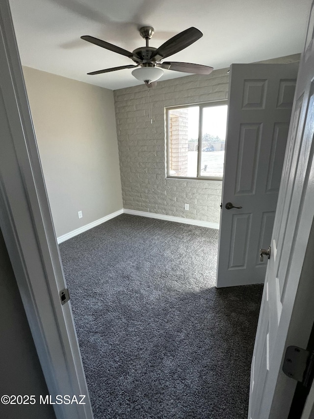 unfurnished bedroom with dark colored carpet, brick wall, and ceiling fan