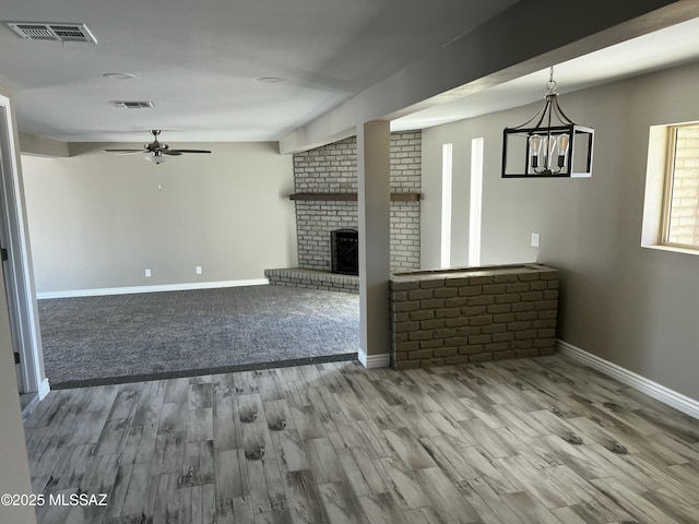 unfurnished living room featuring ceiling fan, hardwood / wood-style floors, and a brick fireplace