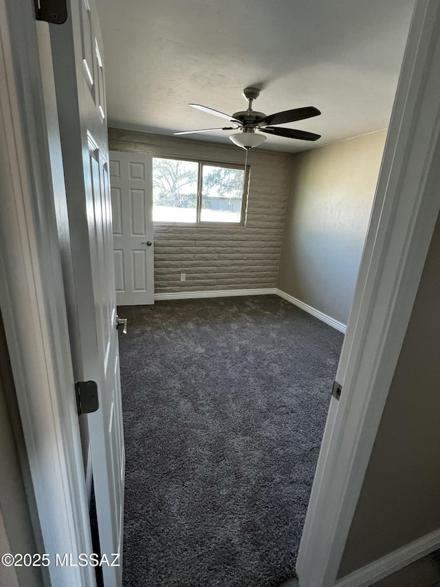 unfurnished room with dark colored carpet and ceiling fan