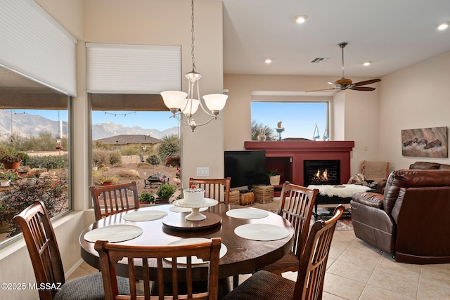 dining space with a mountain view, ceiling fan with notable chandelier, and light tile patterned floors