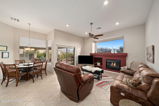 living room featuring ceiling fan with notable chandelier and light tile patterned floors