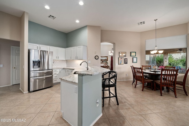 kitchen with white cabinetry, sink, stainless steel fridge, hanging light fixtures, and kitchen peninsula