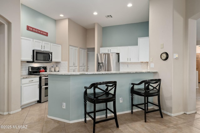 kitchen featuring white cabinetry, a kitchen breakfast bar, kitchen peninsula, and appliances with stainless steel finishes