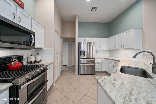 kitchen with light stone counters, sink, white cabinets, and appliances with stainless steel finishes