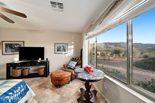 living area featuring a mountain view and ceiling fan