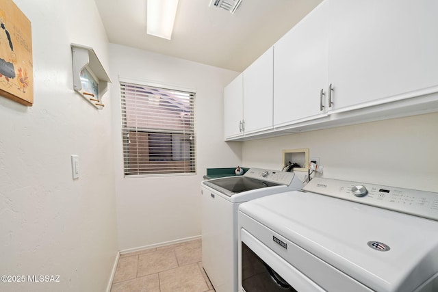 washroom with light tile patterned floors, cabinets, and washing machine and clothes dryer