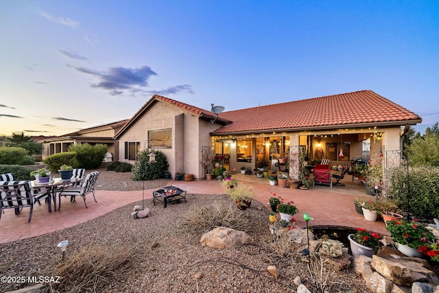 back house at dusk with an outdoor fire pit and a patio area