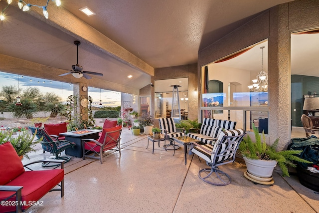 patio terrace at dusk featuring ceiling fan and an outdoor fire pit