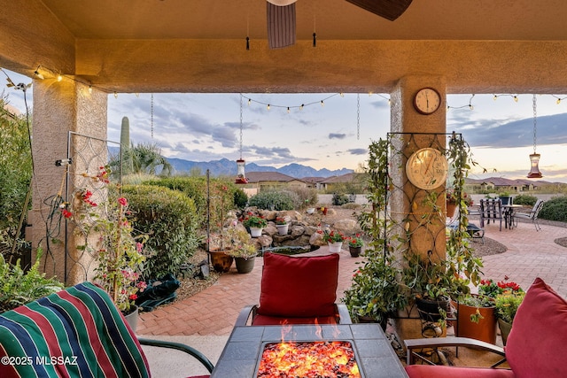 view of patio featuring a mountain view, a fire pit, and ceiling fan