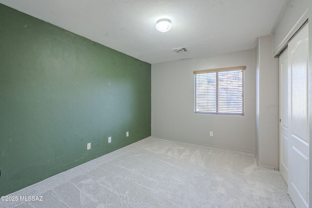 unfurnished bedroom with light colored carpet and a closet