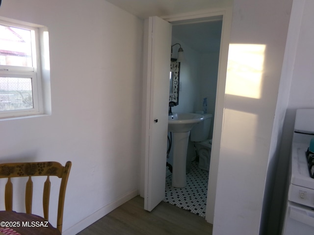 bathroom featuring hardwood / wood-style flooring, washer / dryer, sink, and toilet